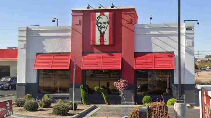 Exterior view of a KFC restaurant with red awnings and Colonel Sanders logo above the entrance.